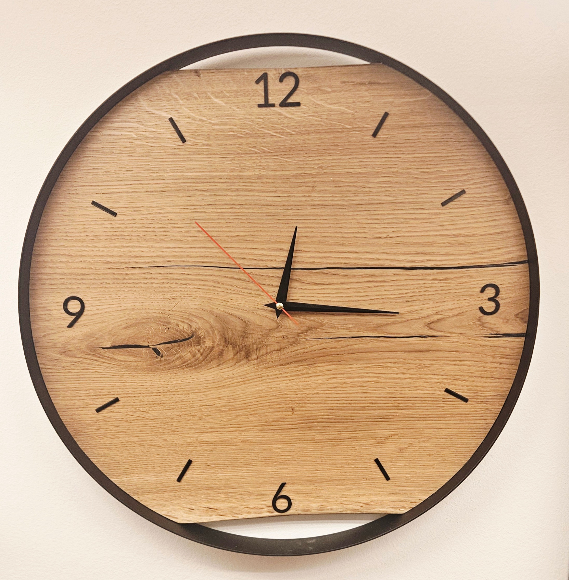Handgefertigte Wanduhr aus massiver Eiche mit schwarzem Stahlreifen und modernem Design für Wohnzimmer oder Büro.
